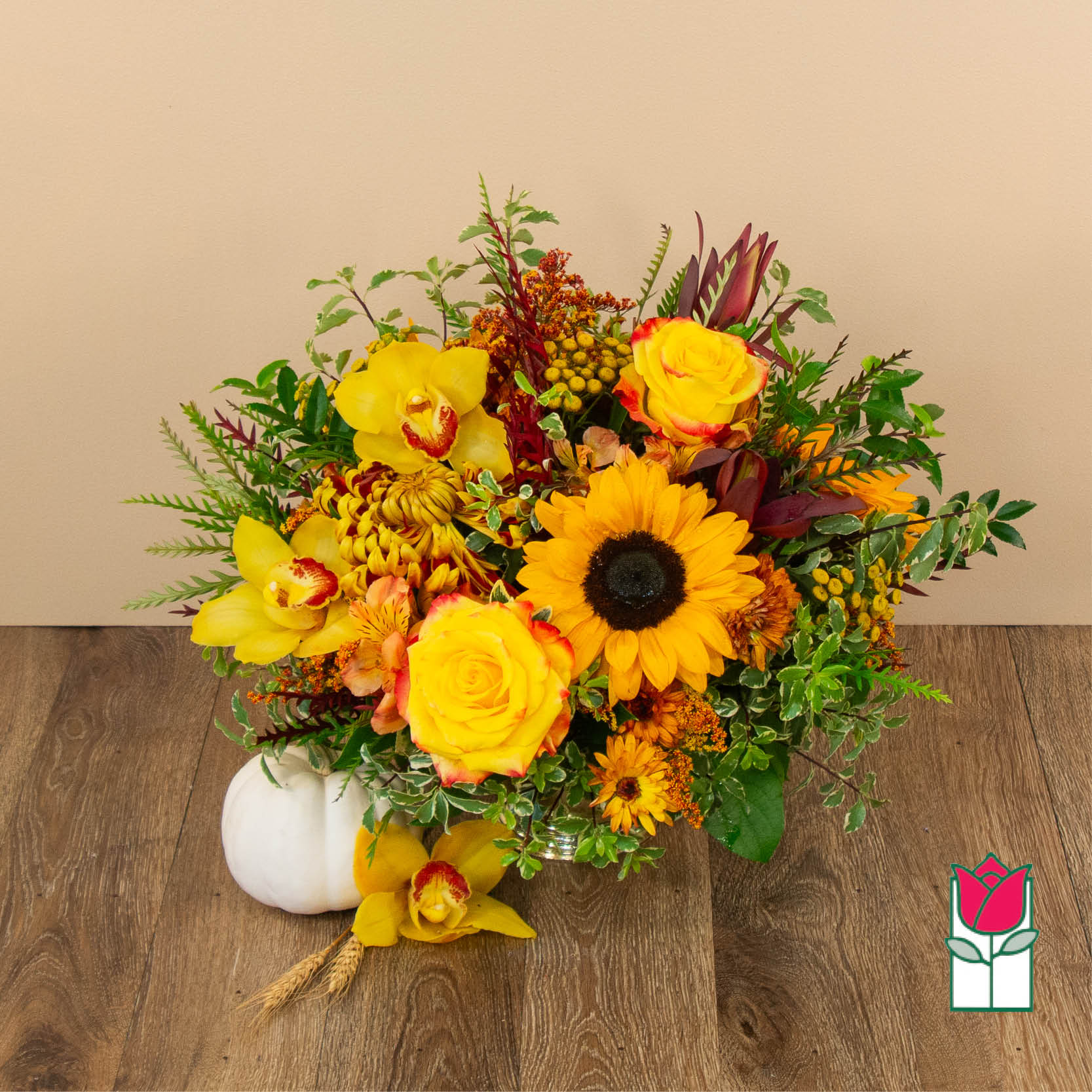 Yellow and orange floral arrangement in a vase with a white pumpkin