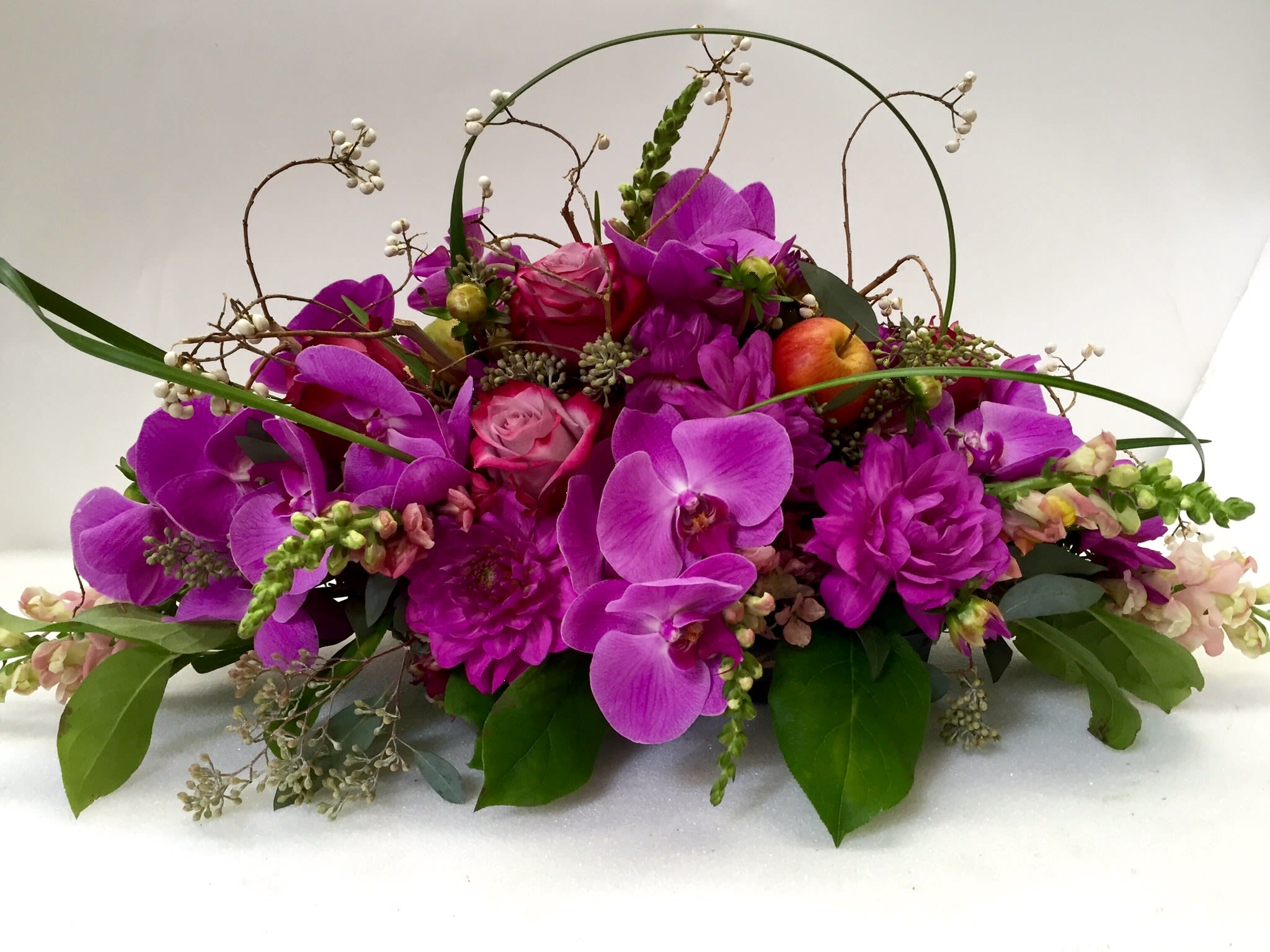 Purple orchid arrangement with apples and arched twigs