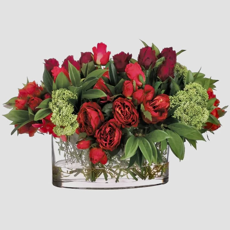 Red roses and red tulips arranged in a clear glass vase