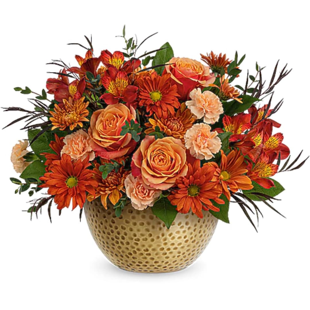 Orange and red mixed flowers in a textured gold vase