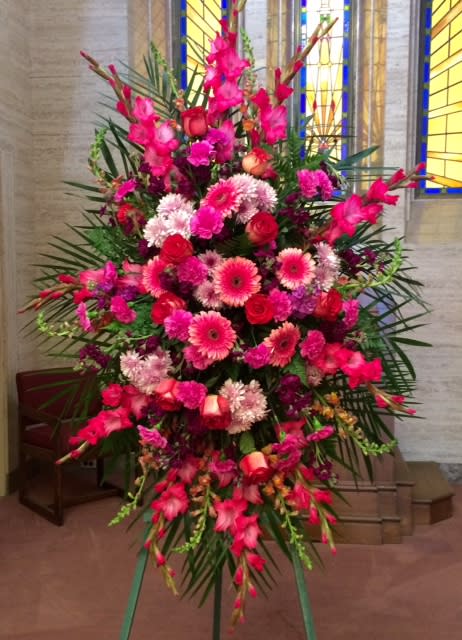 Tall standing spray of pink and red flowers on an easel
