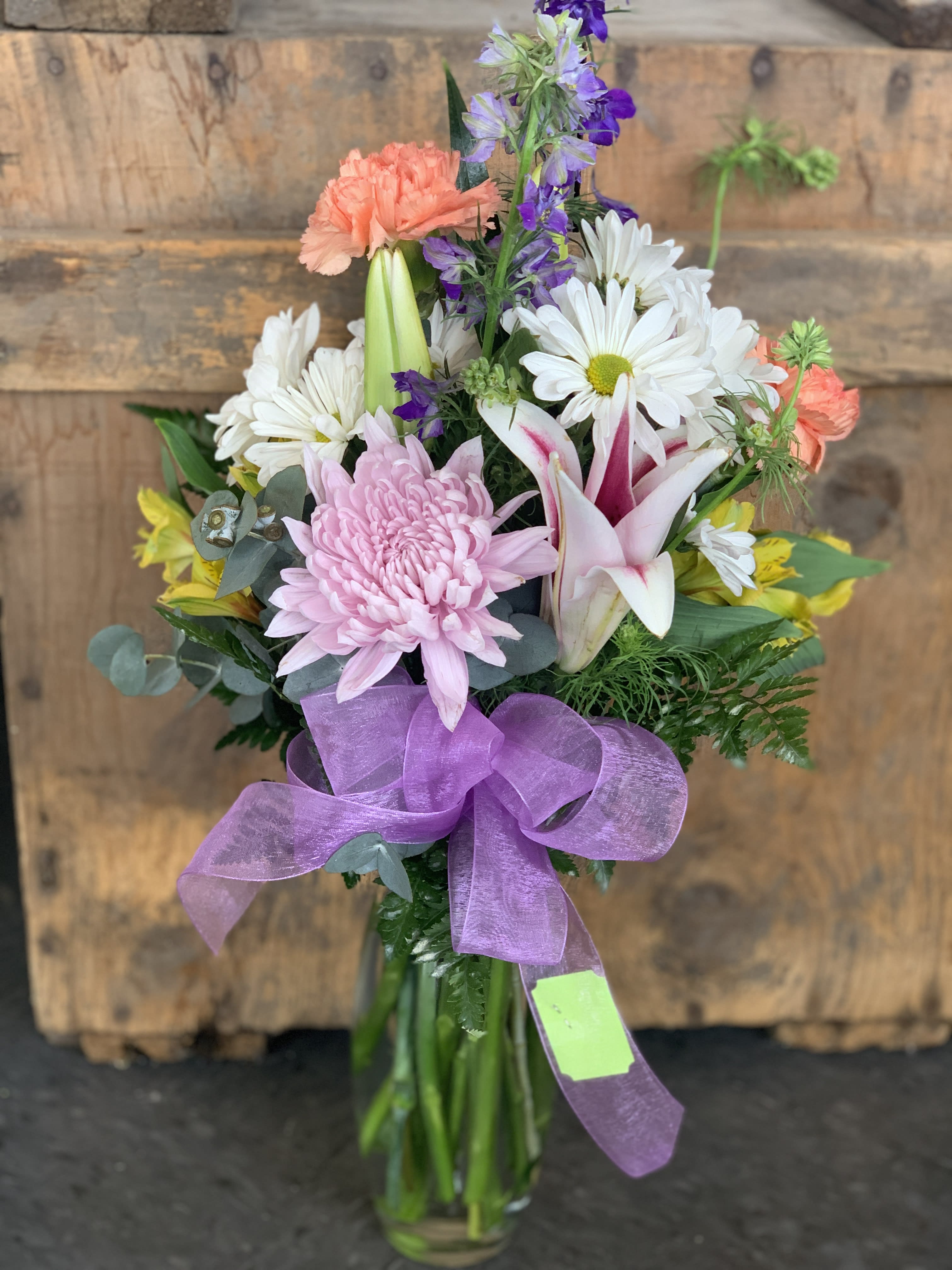 Mixed bouquet with pink, white, purple, and yellow flowers in a glass vase