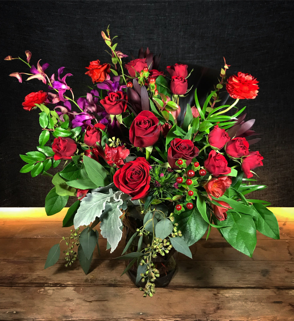 Rich and romantic, this dramatic display of red roses, tropical orchids and