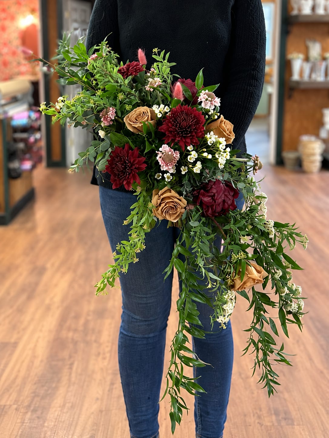 Cascading burgundy and caramel wedding bouquet with pink flowers, white waxflower, and trailing greenery.