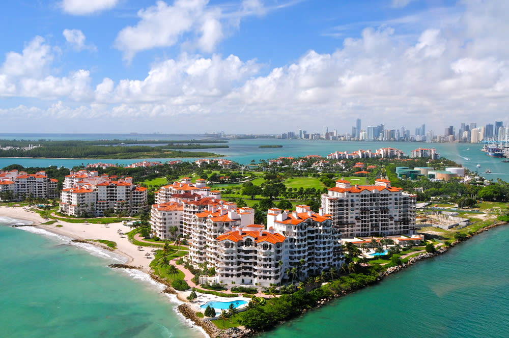 An aerial view of Fisher Island, FL featuring a luxury resort and golf course with an ocean view.