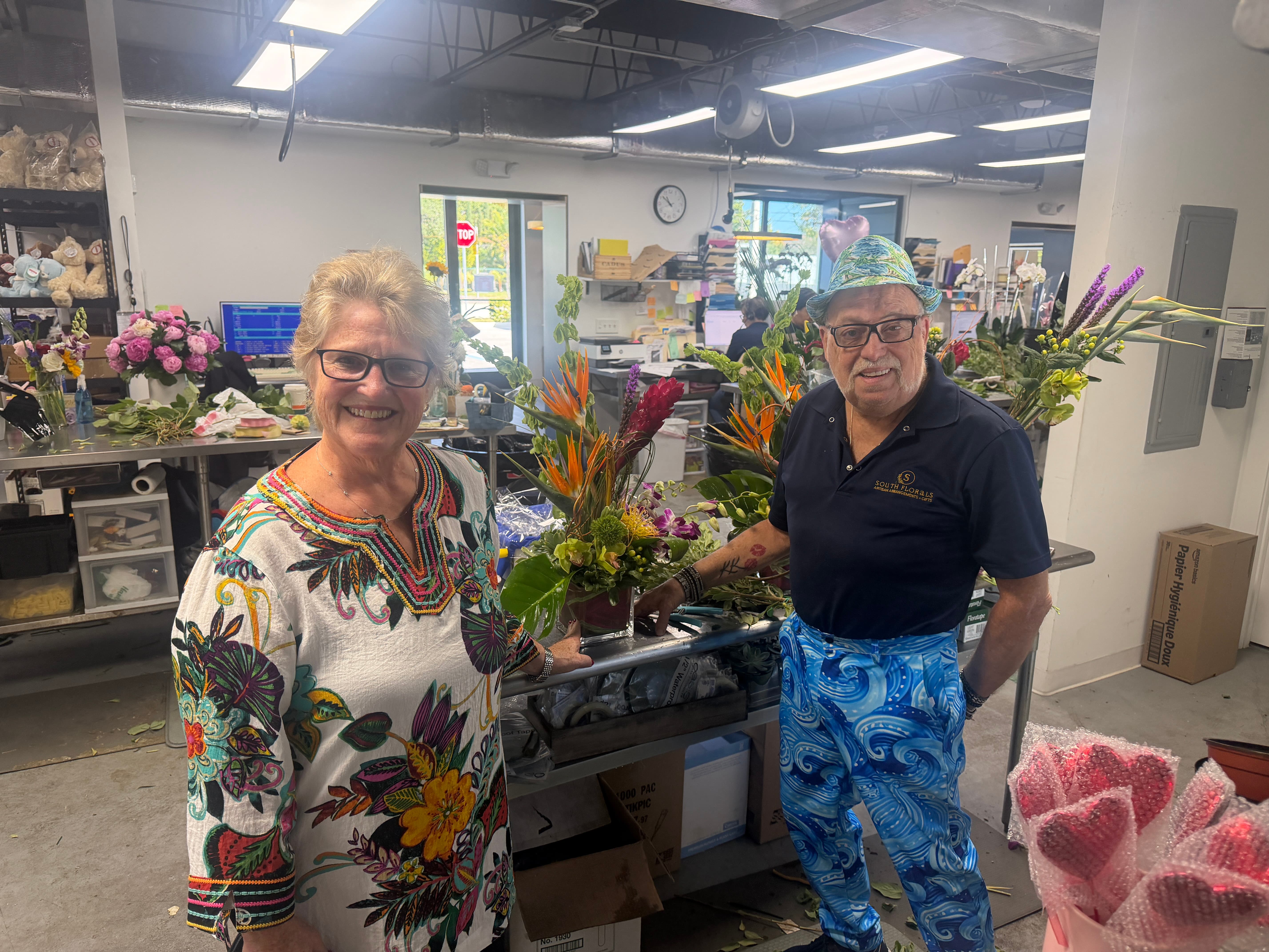 Pair holding a tropical arrangement