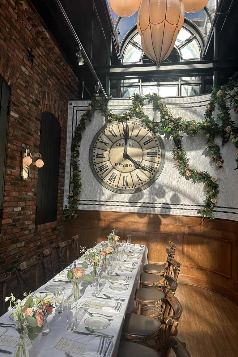 Floral piece trailing up and around a large clock on the wall