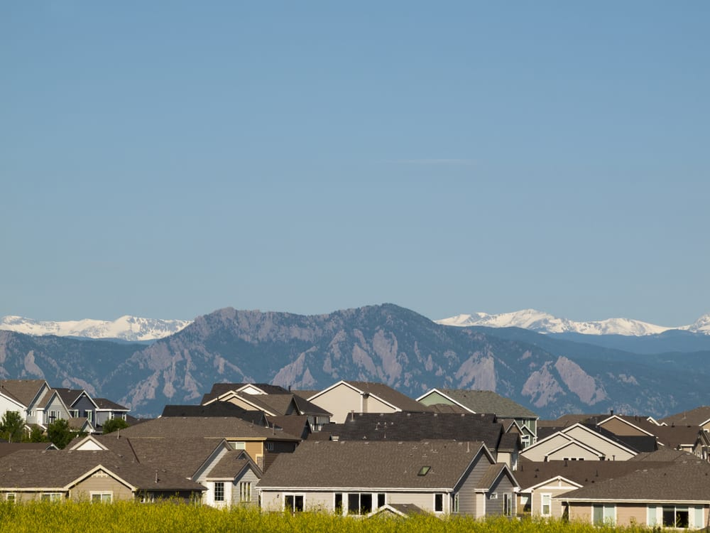 View of roofs in a housing development in Eerie, Colorado with the Rocky Mountains in the background.