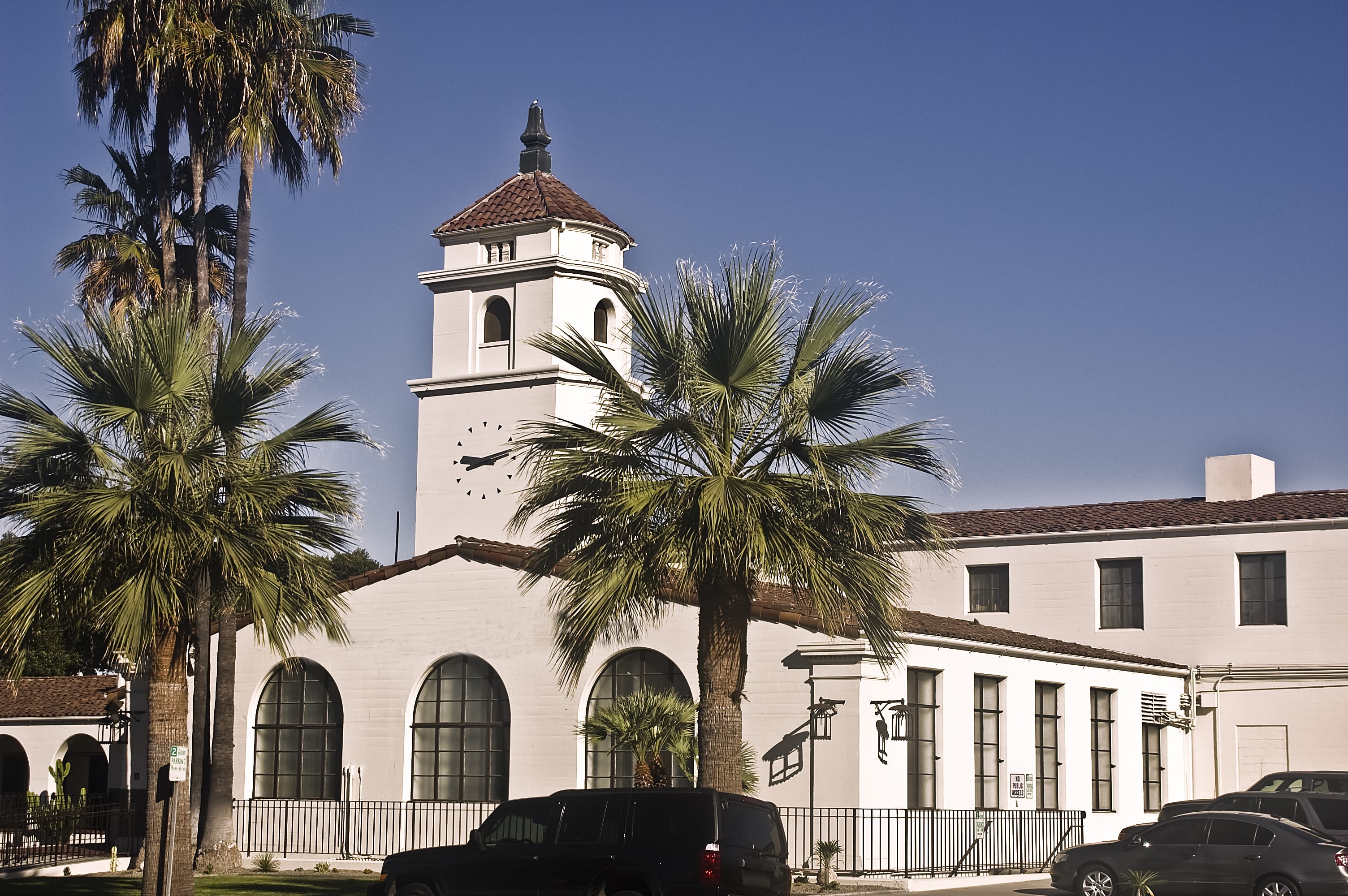 View of an old Spanish mission in Fullerton, California with palm trees in the foreground.