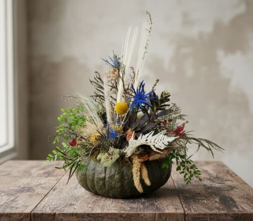 Green pumpkin succulent arrangement with dried flowers, grasses, and succulents, creating a natural Pacific Northwest-inspired fall design.