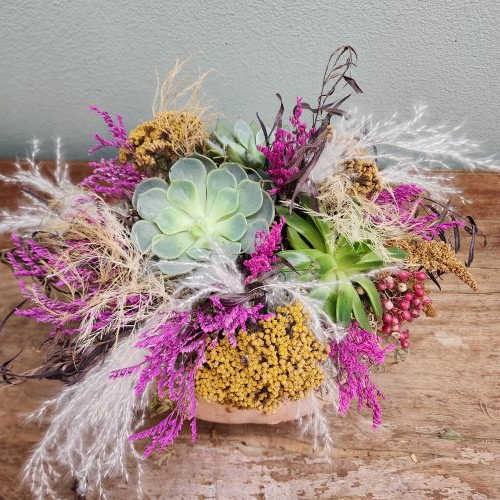 Pumpkin succulent arrangement with bright hot pink dried flowers and succulents, creating a colorful and playful fall design.