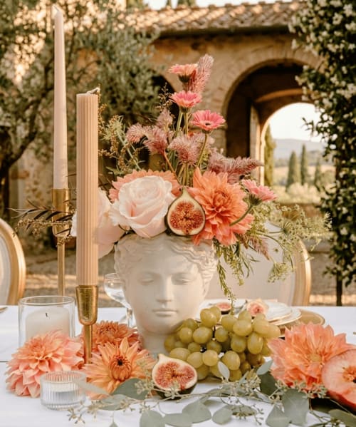 Harvest-inspired tablescape featuring peach dahlias, pink roses and gerbera daisy, cut figs and peaches with peach candles and seasonal accents. 