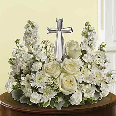 White roses arranged around a standing cross for a graveside service.