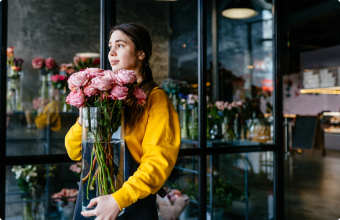 A BloomNation florist carrying a large vase full of pink roses