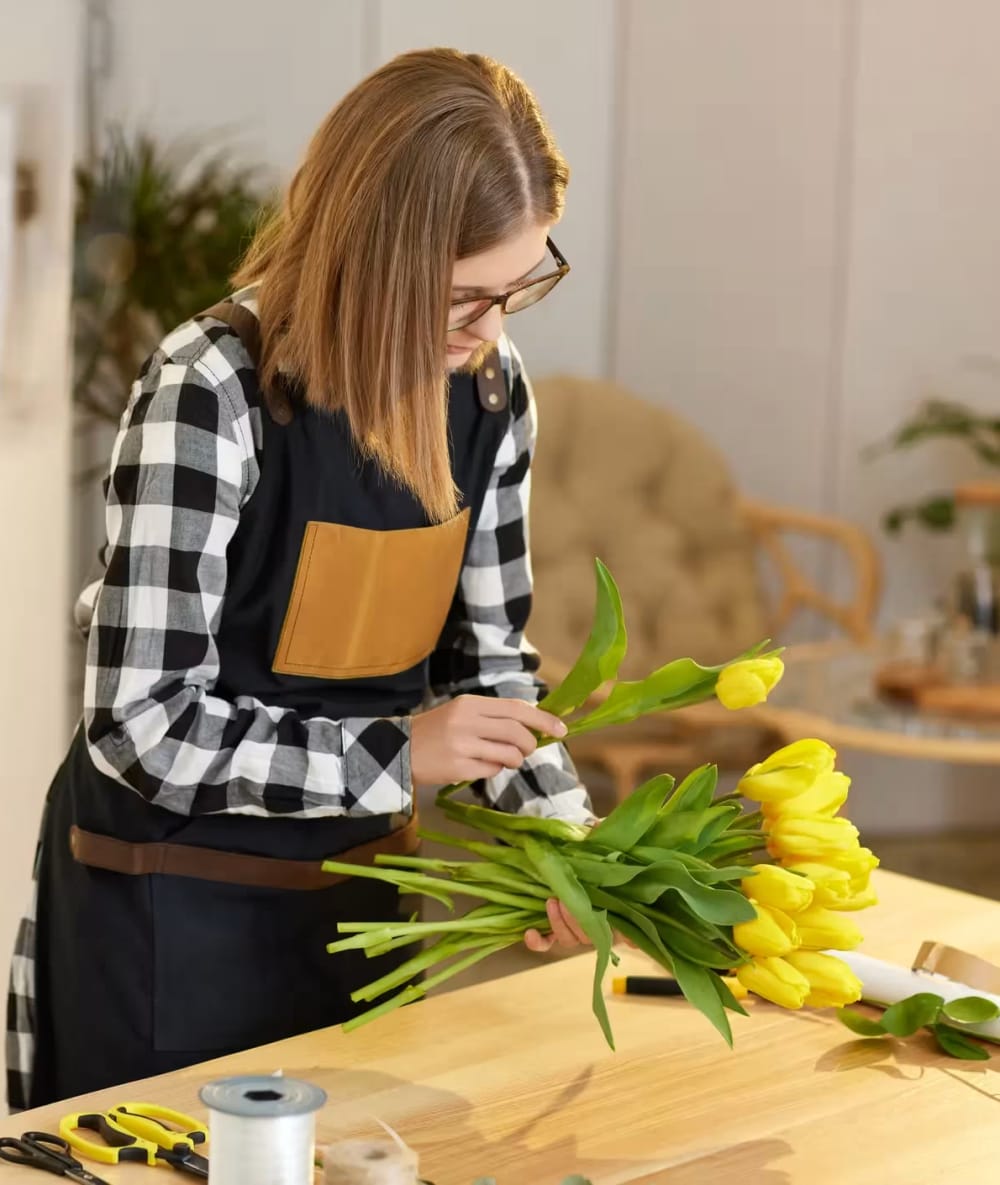 Florist arranging yellow tulips in a bright workspace