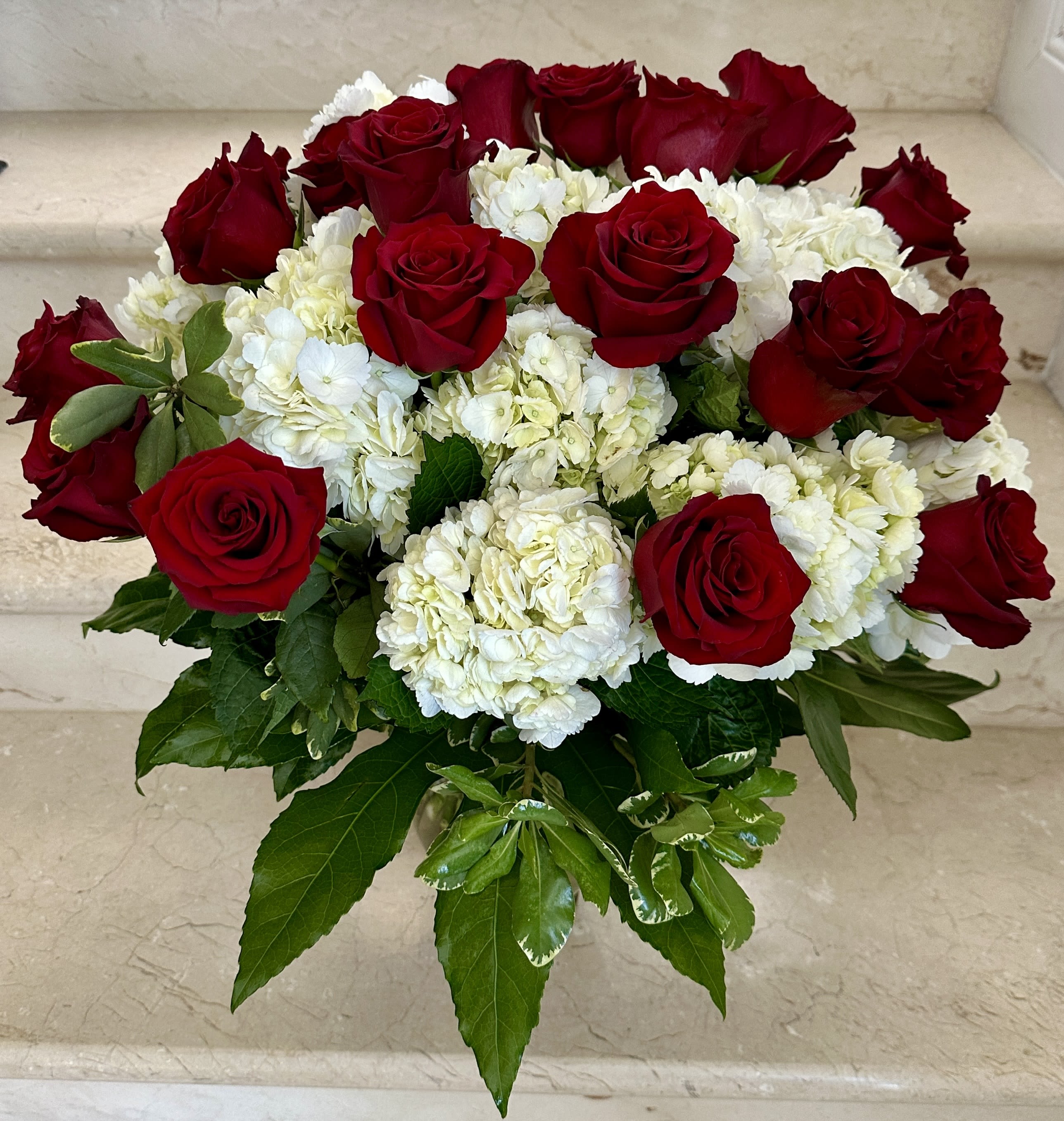 Red Roses and White Hydrangeas arranged in a vase.