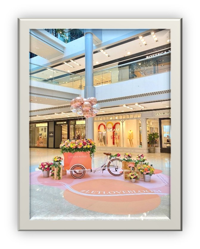 Flower cart with pink, orange and yellow flowers with ballons in mall area 