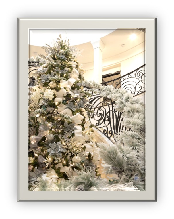White and gold decorated tree next to large staircase