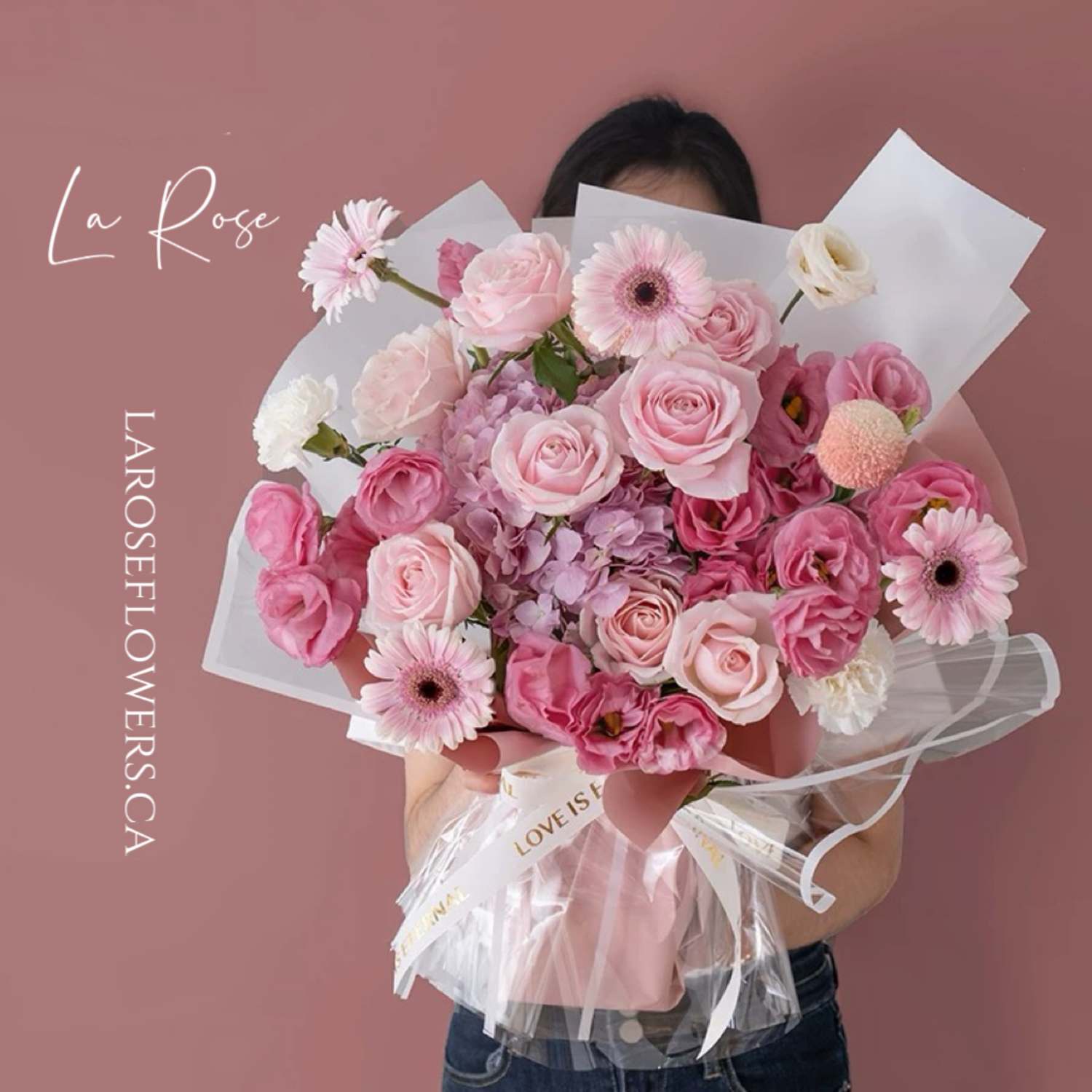 Close-up of a luxurious bouquet featuring vibrant red roses, delicate hydrangeas, and white alstroemerias, elegantly arranged and wrapped in soft pastel paper on a wooden counter