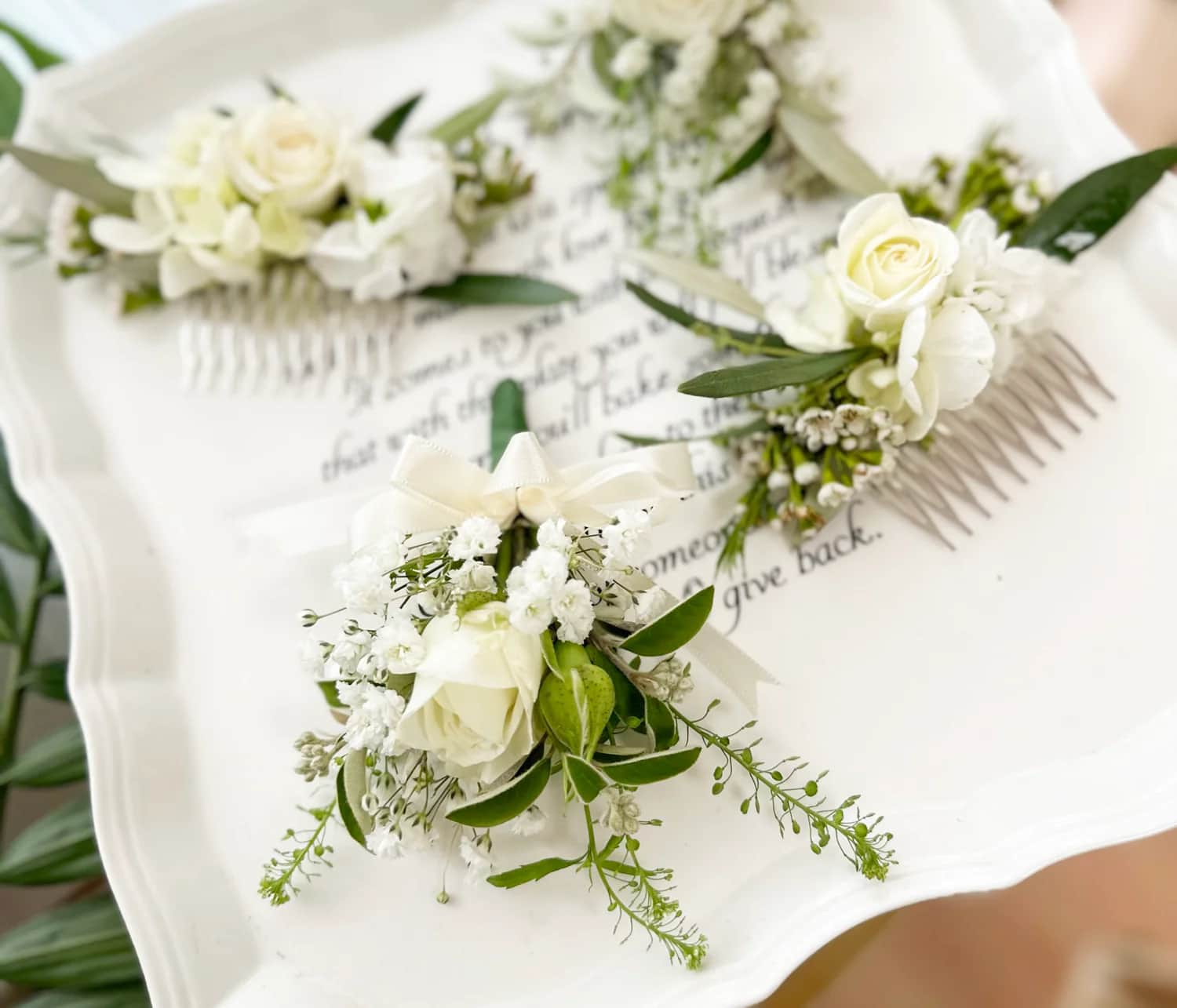 White boutonniere and two white combss with live arrangements