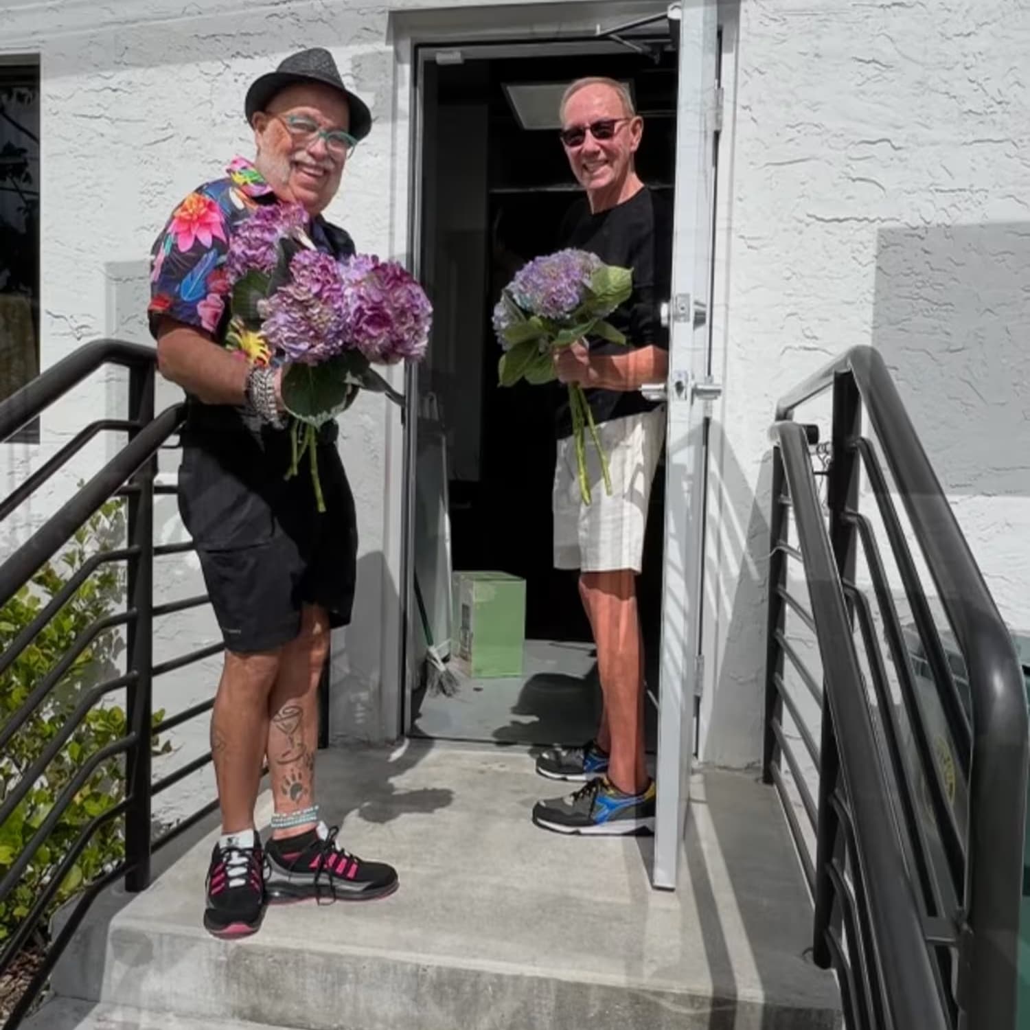 Pair smiling outdoors with flower arrangements