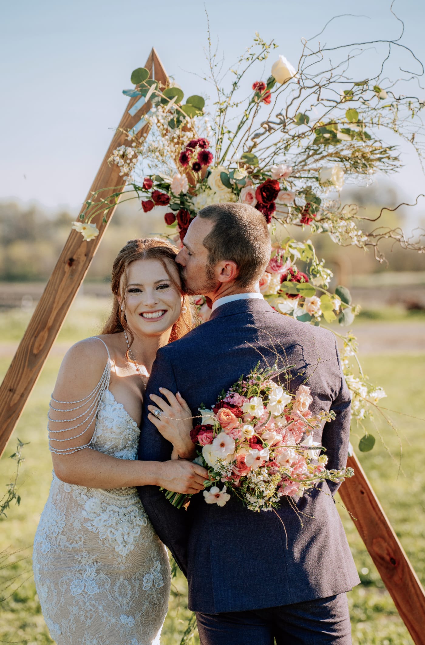 Bride holding a lush pink, coral, burgundy and ivory garden-style wedding bouquet.