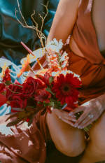 Close-up of a red and orange bouquet with roses, gerbera daisies and textural flowers.