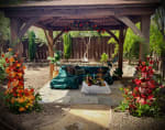 Large orange and red floral installation with roses, gerbera daisies, citrus fruit and greenery surrounding an outdoor lounge.