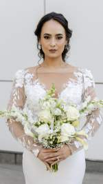 Bride holding an elegant all-white bouquet with roses, calla lilies and delicate white flowers.