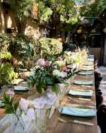 Pink roses and white flowers with greenery arranged along an elegant outdoor wedding reception table.