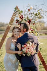 Bride holding a lush pink, coral, burgundy and ivory garden-style wedding bouquet.