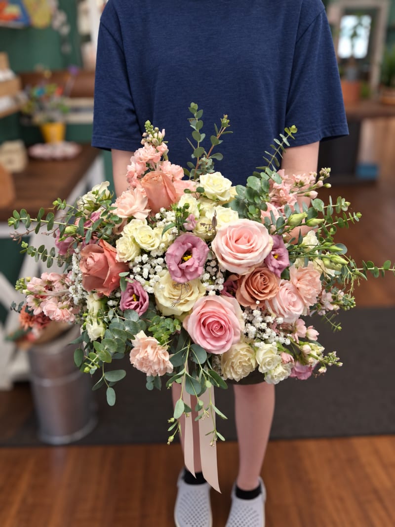 Blush and ivory wedding bouquet with roses, lisianthus, and eucalyptus.