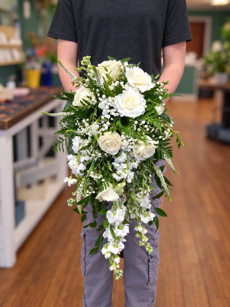 White cascading wedding bouquet with roses, trailing white flowers, and greenery.