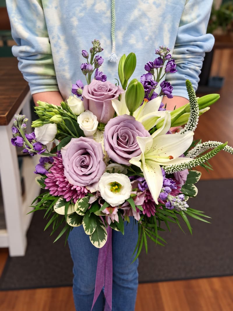 Lavender rose and white lily wedding bouquet with purple flowers and variegated greenery.