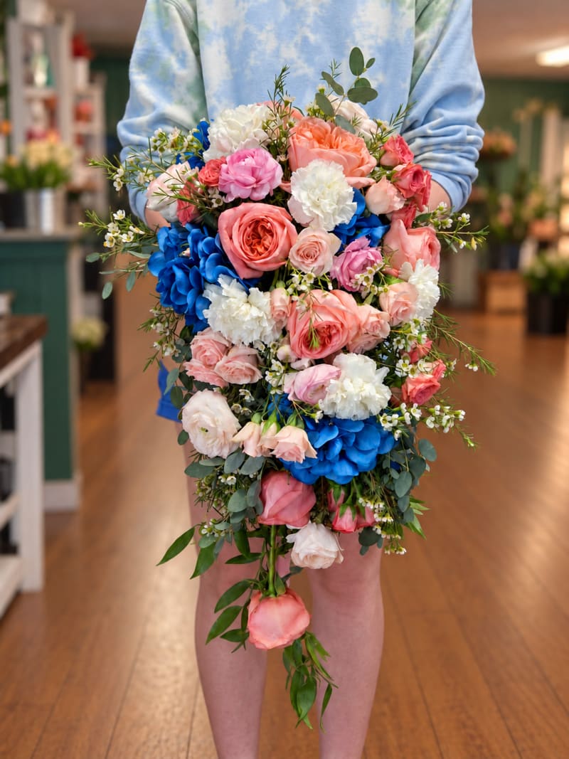 Cascading coral, pink, white, and blue wedding bouquet with roses and hydrangea.
