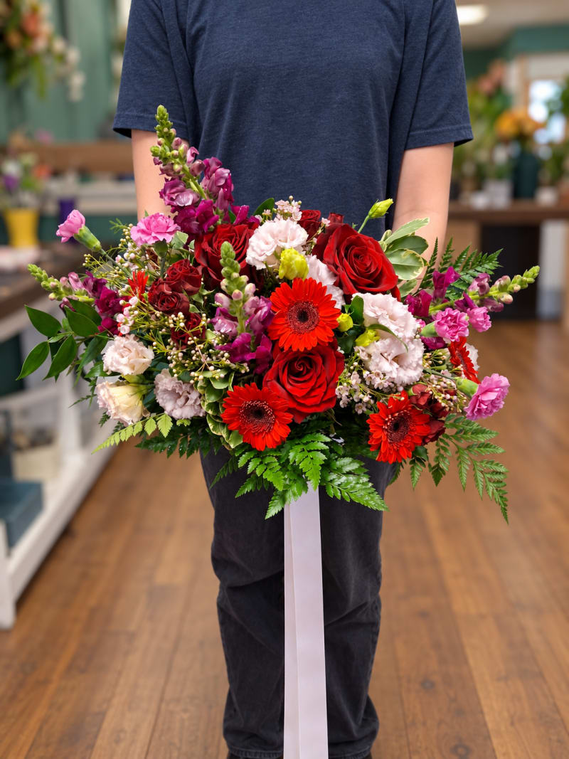 Red, pink, and purple wedding bouquet with roses, gerberas, and greenery.