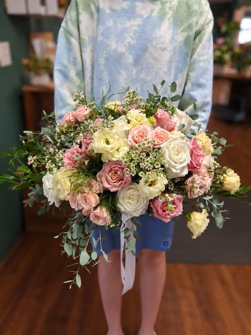 Blush and ivory rose wedding bouquet with white flowers and trailing greenery.