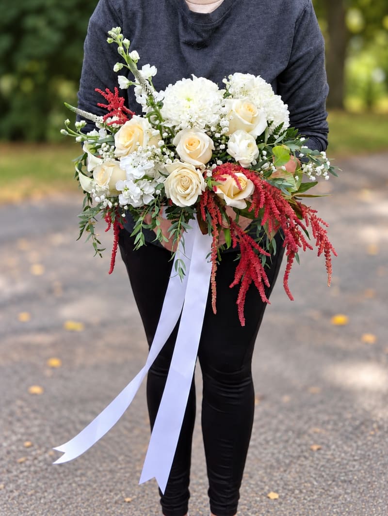 Ivory wedding bouquet with roses, white flowers, and trailing red amaranthus.