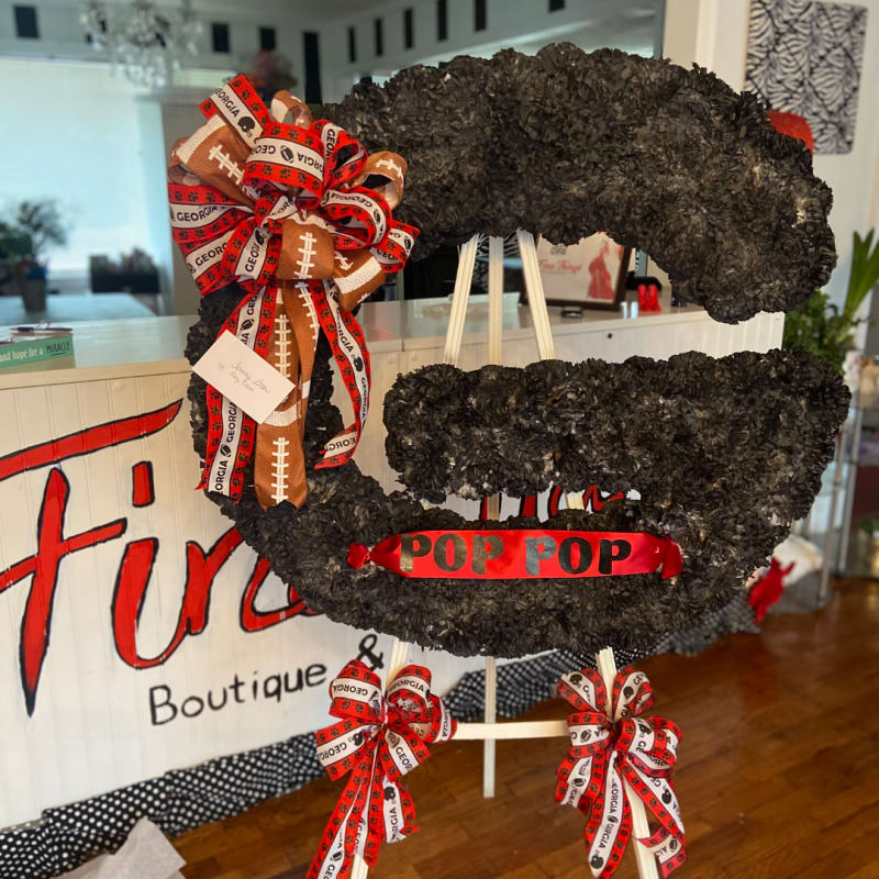 Custom football-themed standing floral tribute with red and gold ribbon.