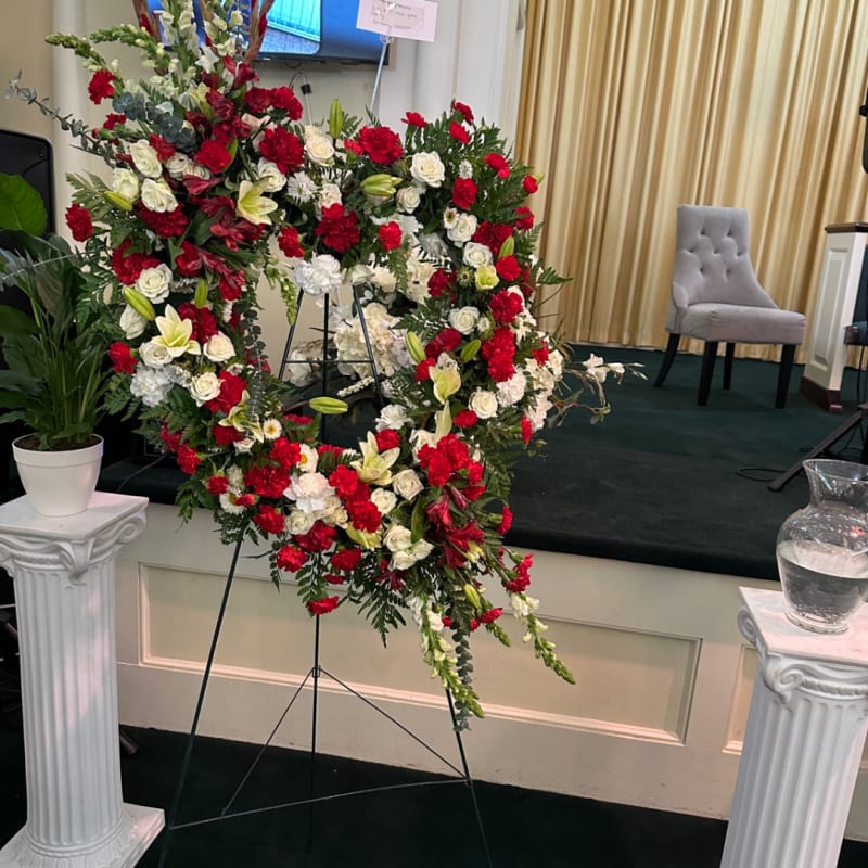Red and white open-heart floral wreath on an easel.