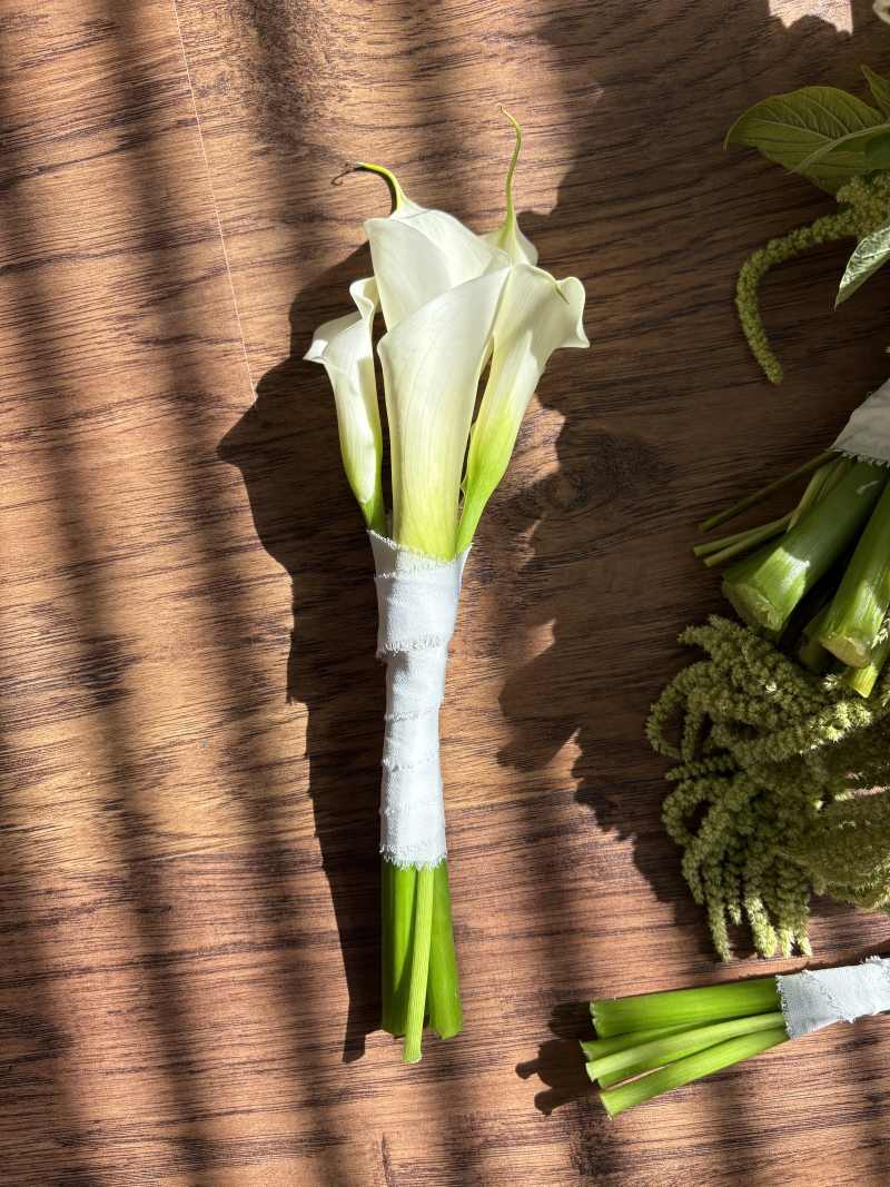 Designed with sleek white calla lilies, the bouquet offers a clean, modern silhouette that feels both refined and effortlessly elegant.