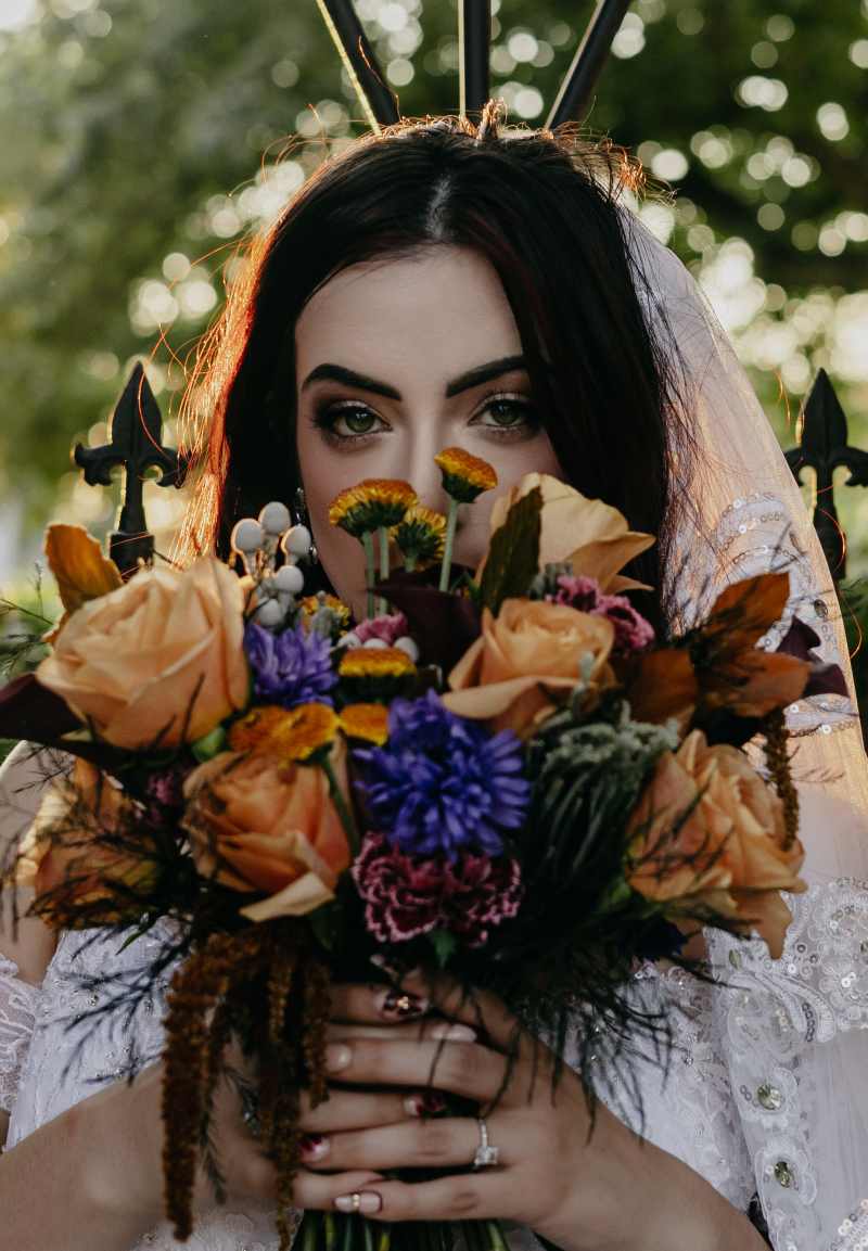 Featuring black-tinted greenery, copper beech foliage, silver-gray brunia, brown button mums, coffee-colored roses, nude-toned carnations, striking purple anemones, and cascading bronze amaranthus,