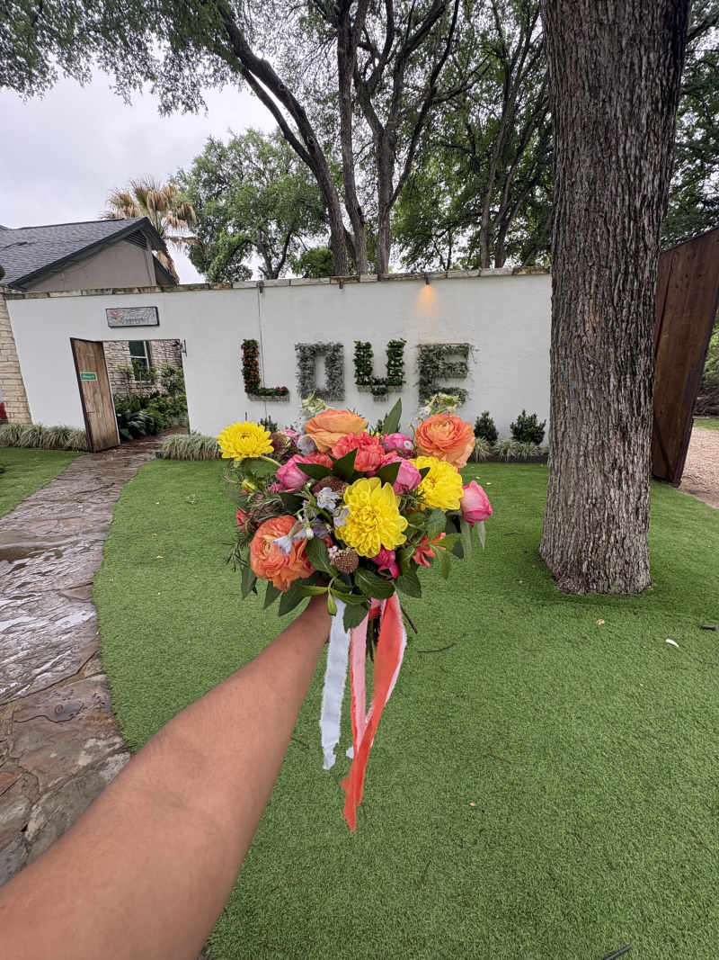 Fragrant bay leaves, rosemary, and mint add an organic, freshly gathered feel,sunny yellow dahlias, hot pink garden spray roses, pink scabiosa, airy light blue delphinium, and vibrant orange ranunculus