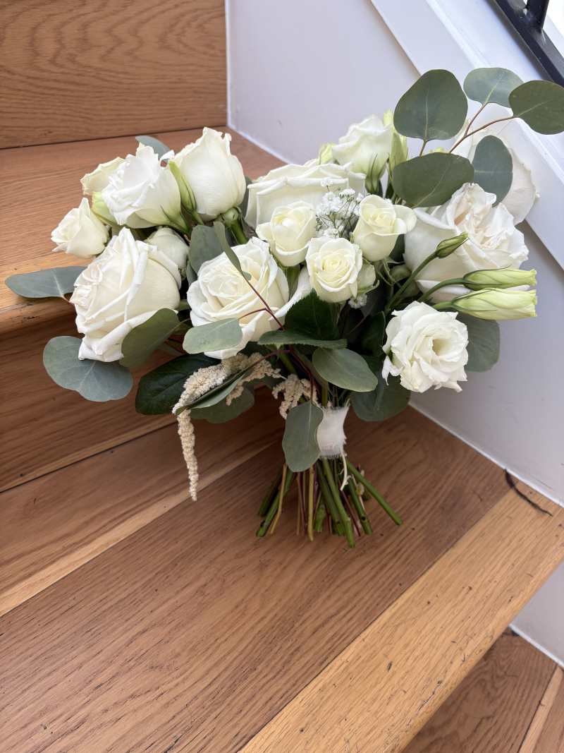 this elegant bridal bouquet features timeless white roses, delicate white lisianthus, preserved hanging amaranthus, and silver dollar eucalyptus.
