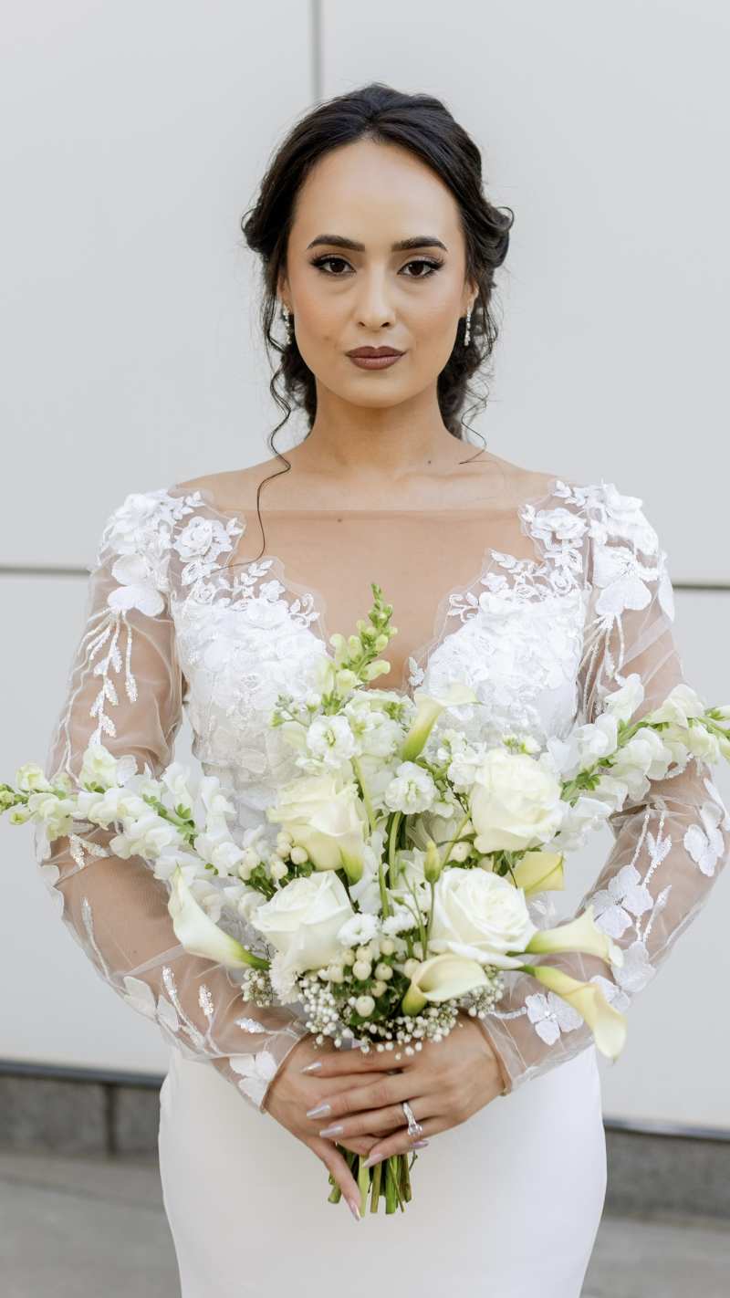 Bride holding an elegant all-white bouquet with roses, calla lilies and delicate white flowers.