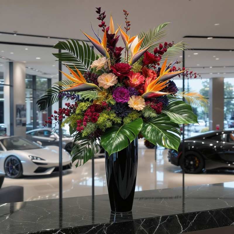Tropical hotel floral arrangement in a black vase.