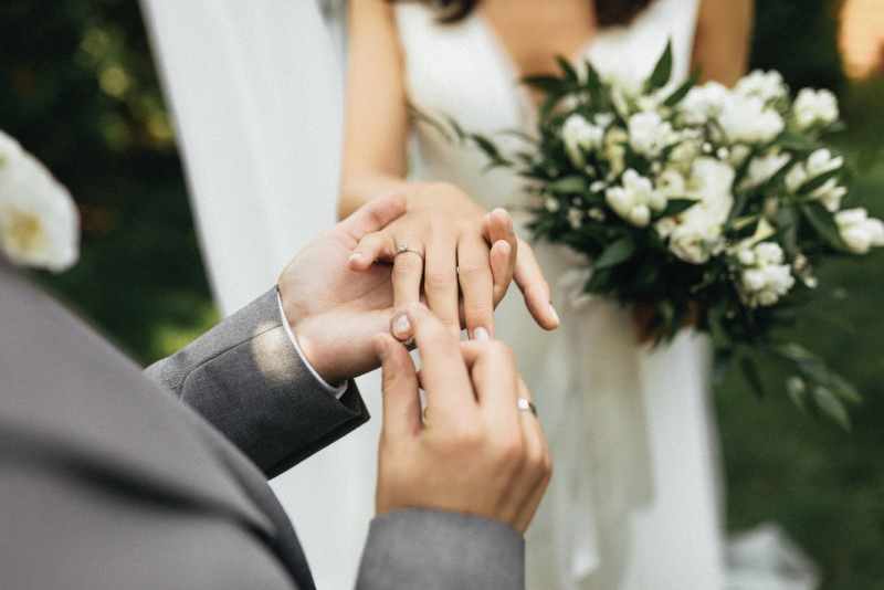 Bride holding a white bridal bouquet during a ring photo.