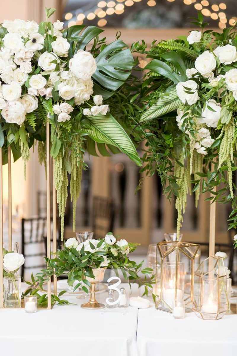 Green and white wedding floral installation with hanging greenery.