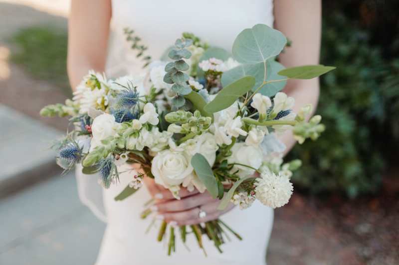 White and green bridal bouquet held by a bride.