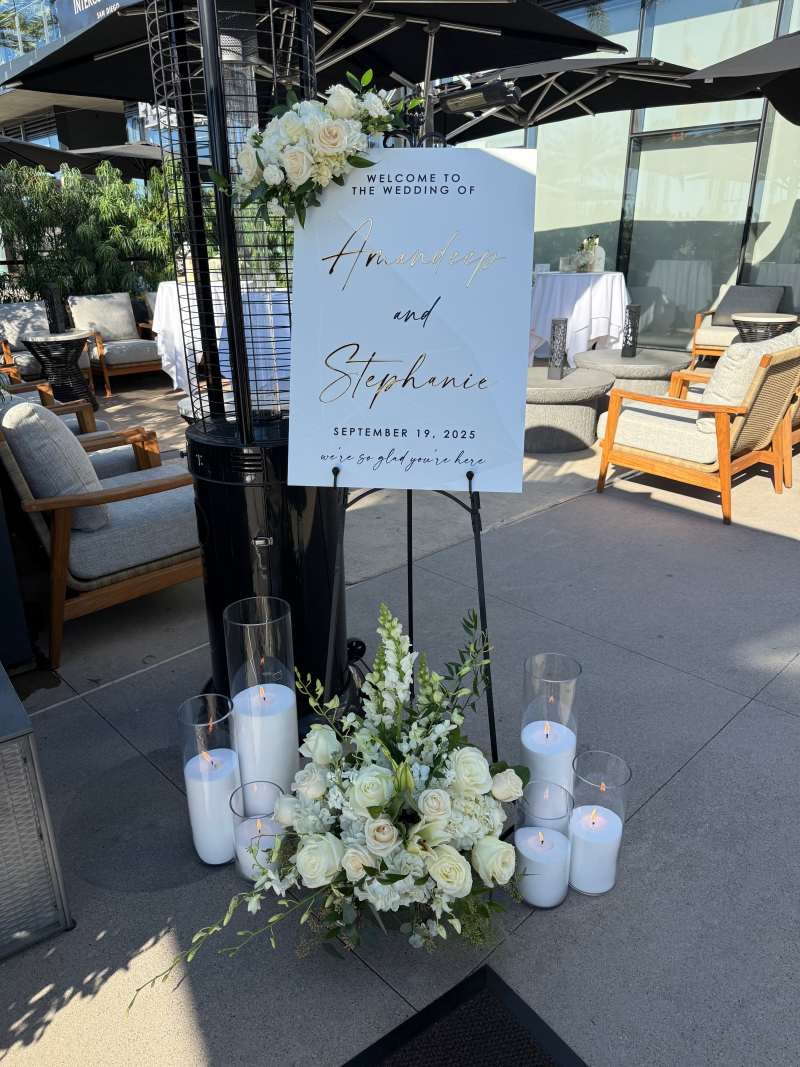 Elegant wedding welcome sign displayed with white roses, hydrangeas, snapdragons, candles, and floral accents at the InterContinental San Diego Bayview Terrace.